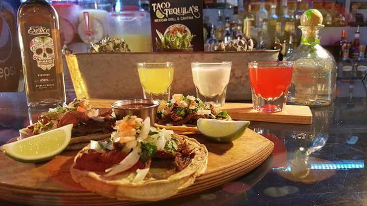 Tacos, salsas, and cocktails on a dining table.